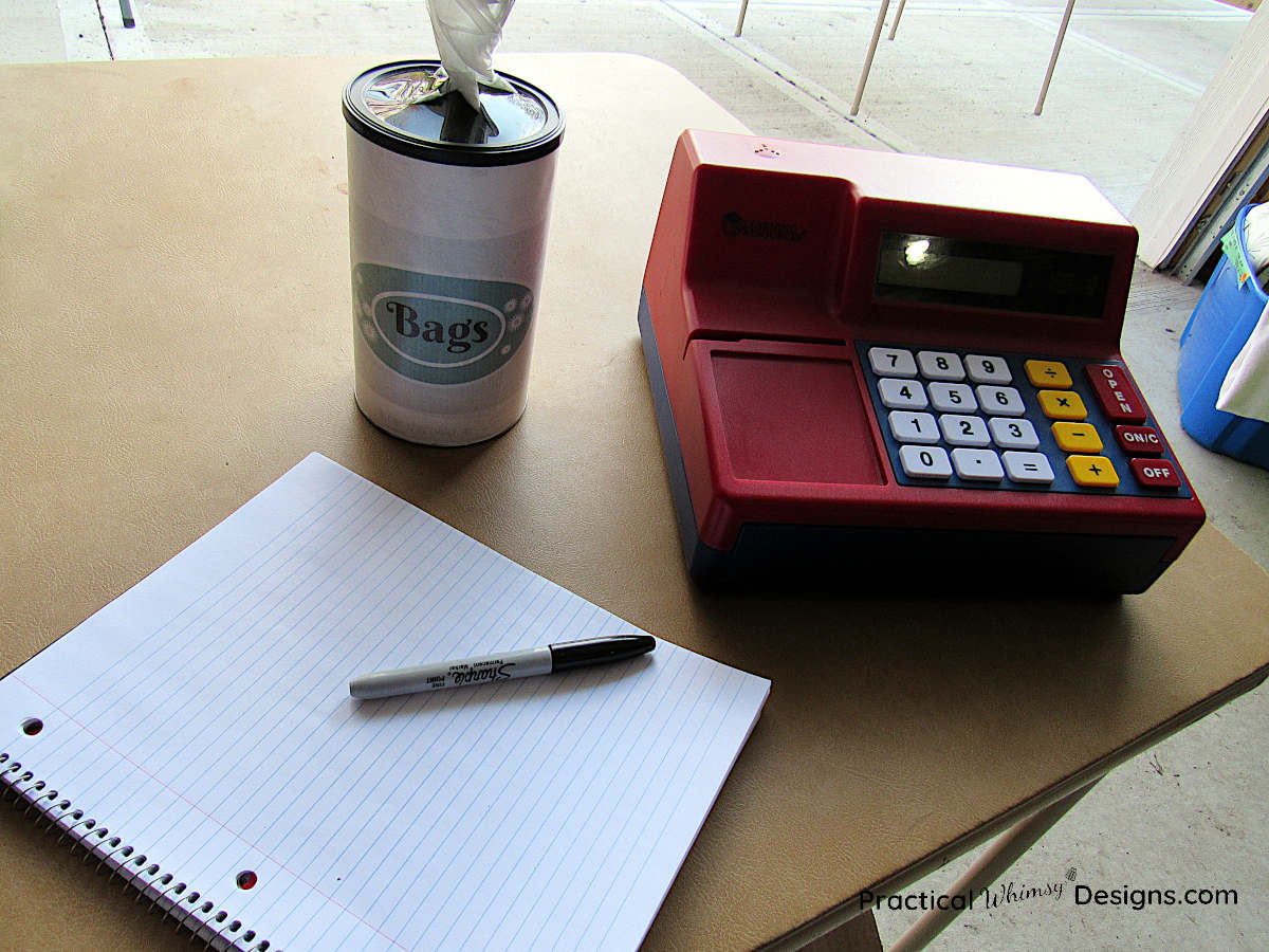 Toy cash register, notebook, and bags for garage sale organization