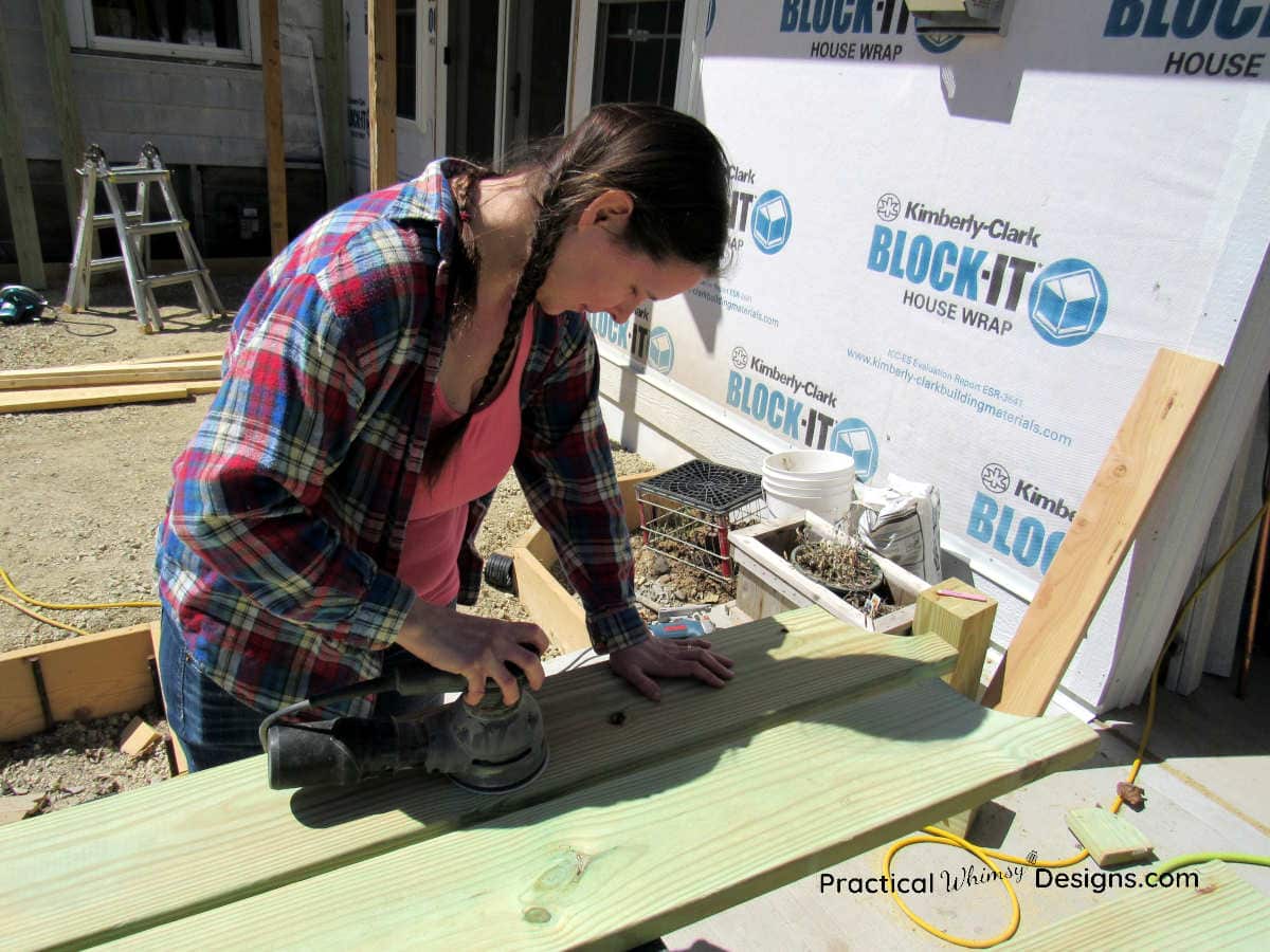 Lady sanding a board with an electric sander