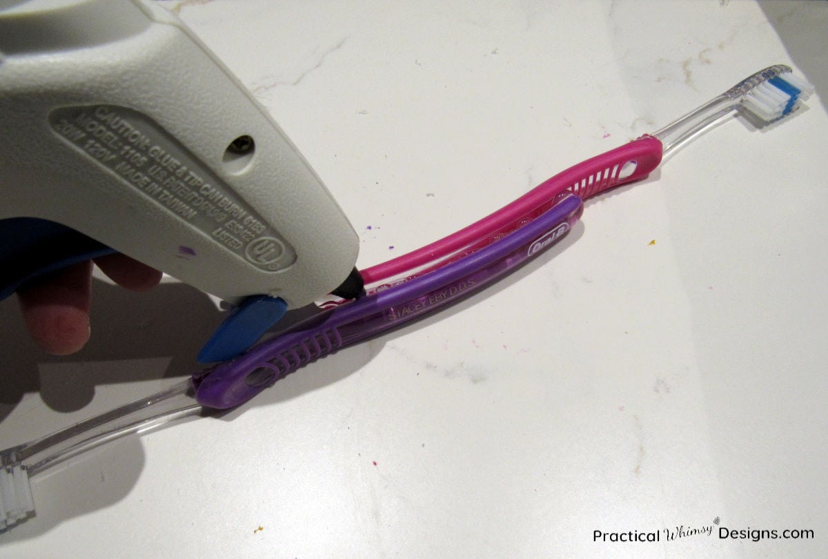 Gluing two tooth brushes together with hot glue gun