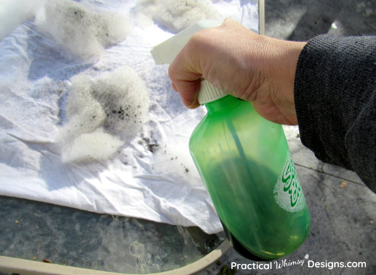 Using spray bottle to spray black water paint on shirt