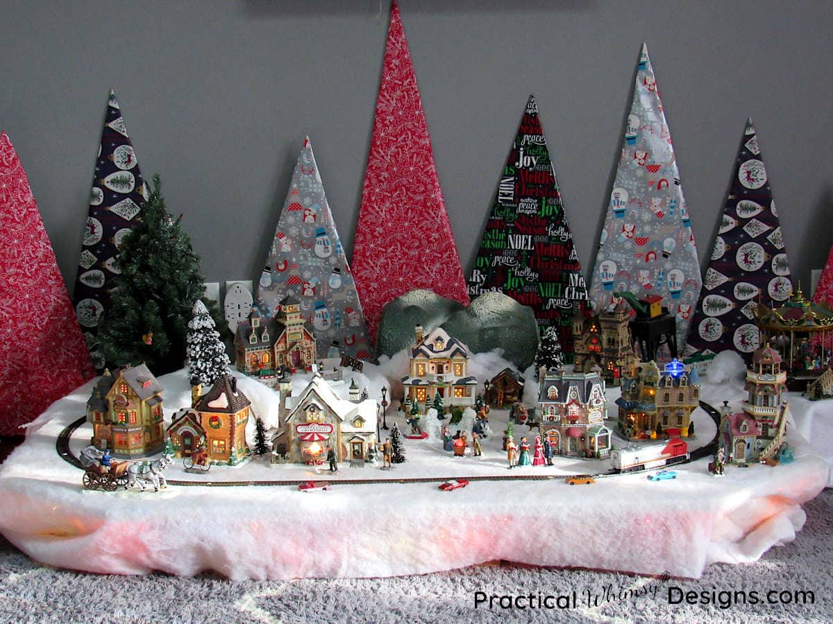 Cardboard Christmas Trees Behind Christmas Village