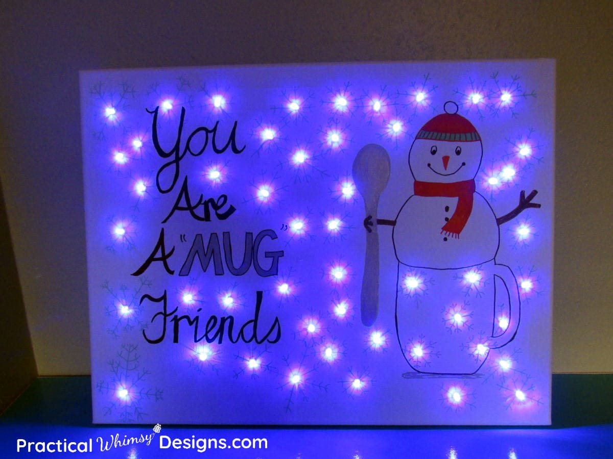 DIY snowman lighted canvas art with blue lights lit.