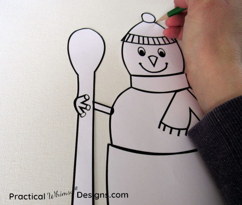 Hand tracing snowman on canvas with a pencil