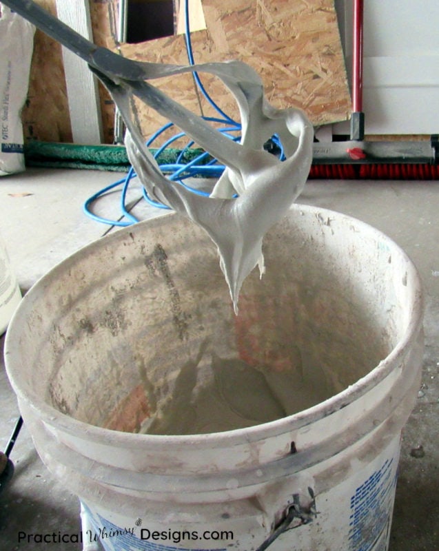 Mortar dripping off a mixing paddle into a bucket