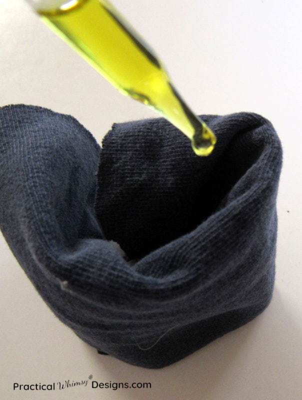 Dropper adding essential oil to t-shirt fabric