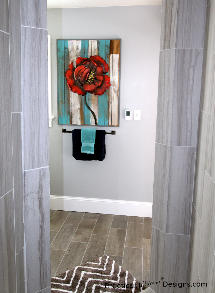 Red Flower picture hanging above blue towels