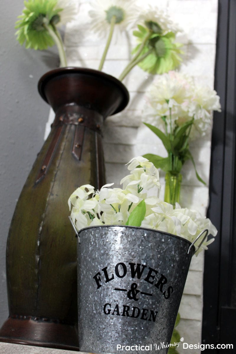 Green and White Flowers in vase and metal flower bucket