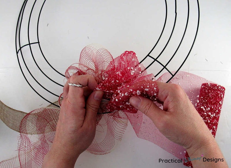 Adding loops of second color of deco mesh onto wreath.