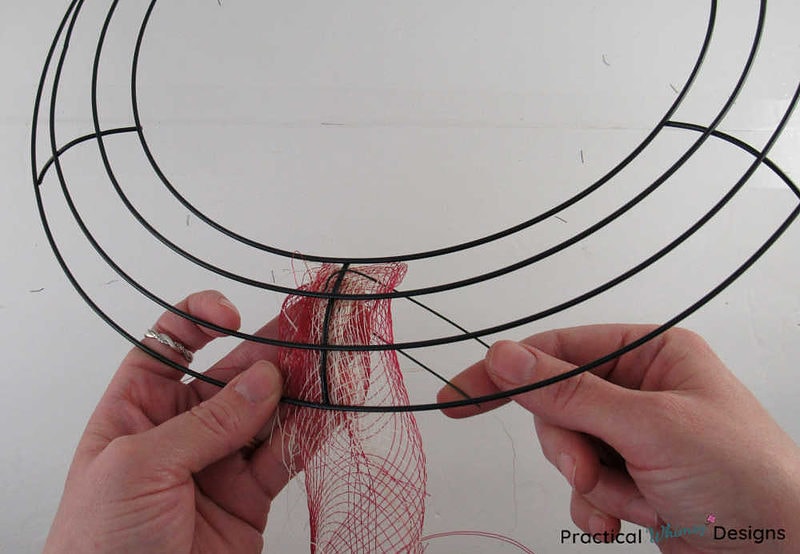 Attaching deco mesh to wreath frame with floral wire.