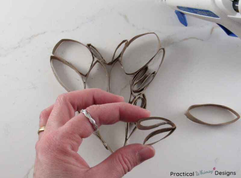 Hand bending toilet paper roll circle in half for 3D paper heart art.