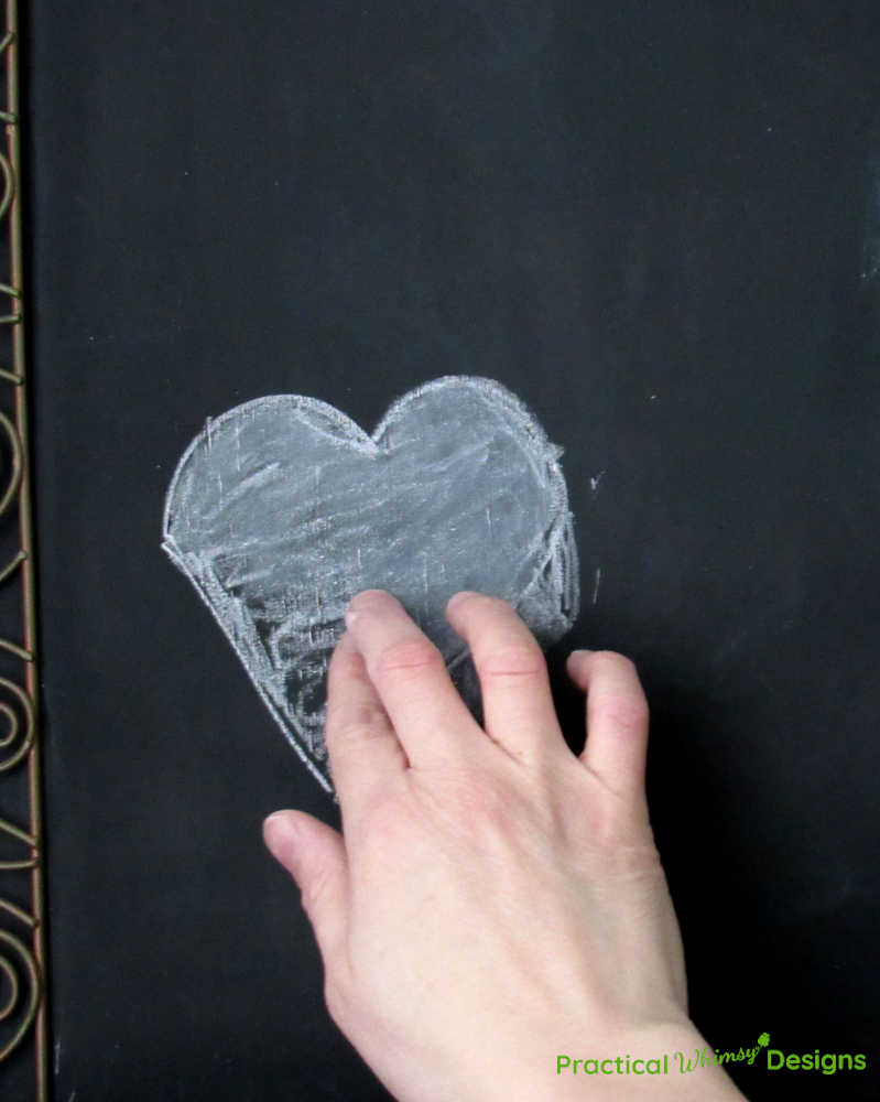 Blending chalk on chalk heart with finger