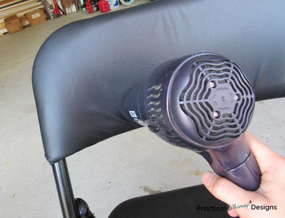 Heating black vinyl chair with a hair dryer.