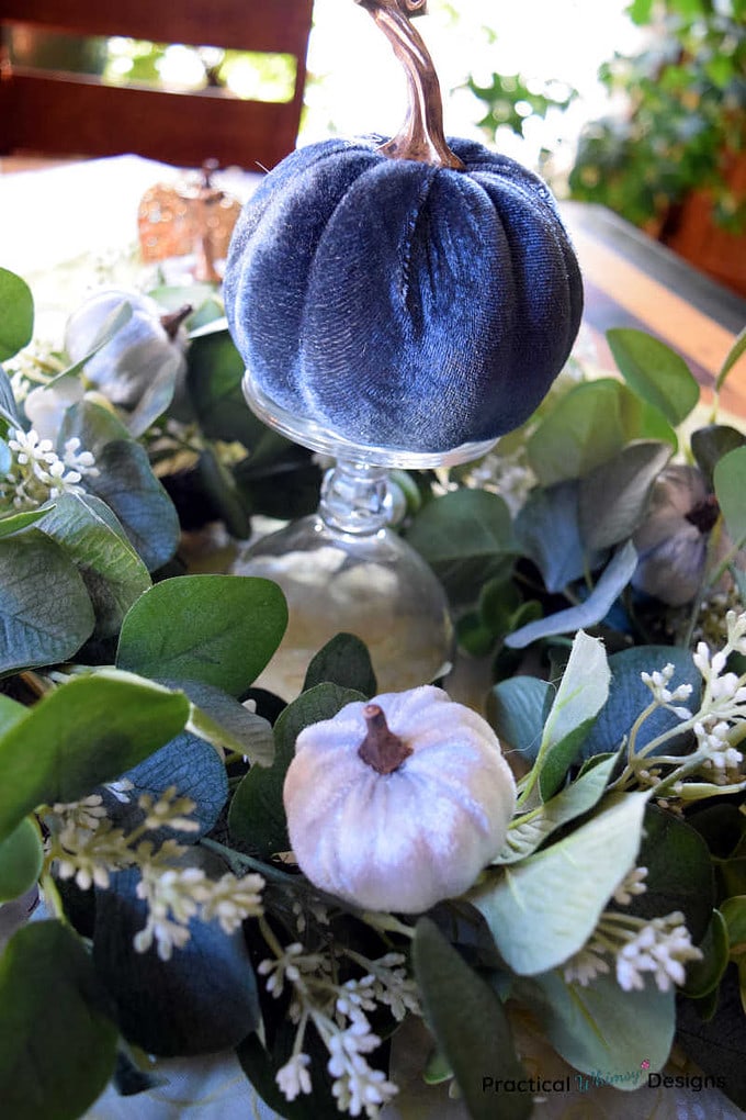 Blue velvet pumpkin on upside down goblet and green wreath table centerpiece.