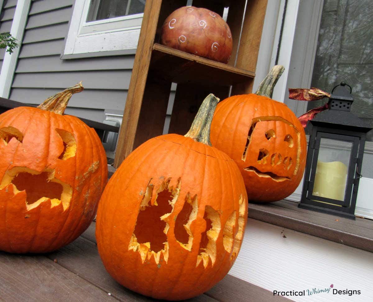 Bat and boo carved pumpkins on porch steps.