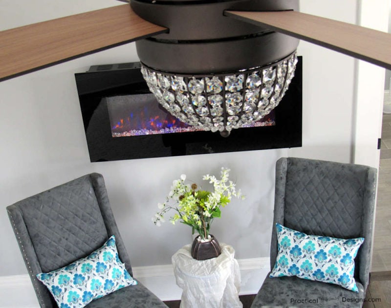 Grey chairs underneath electric fireplace with small table and flowers