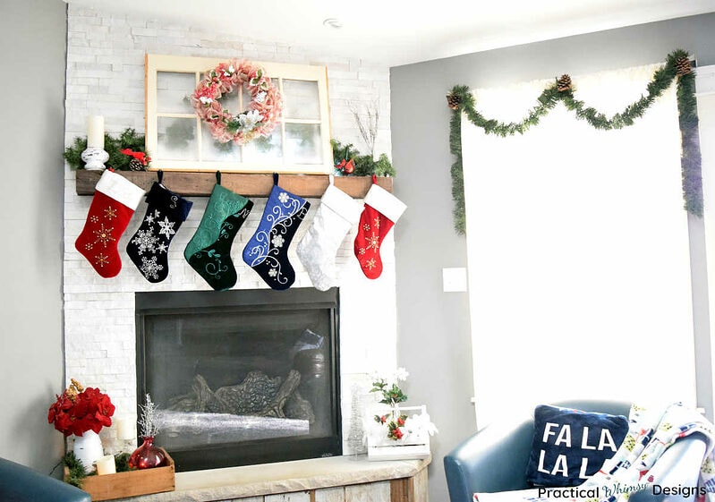 Fireplace decorated for Christmas with stockings, wreath and flowers.