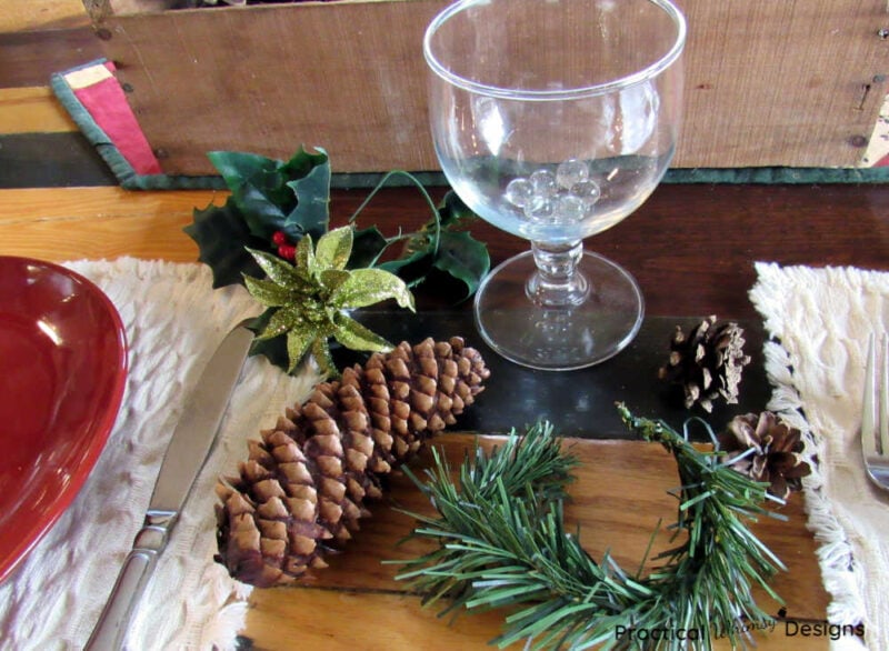 Pinecones, glass, flowers, and pine bough on table