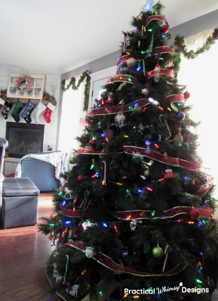 Christmas tree decorated with red ribbon and ornaments in family room.