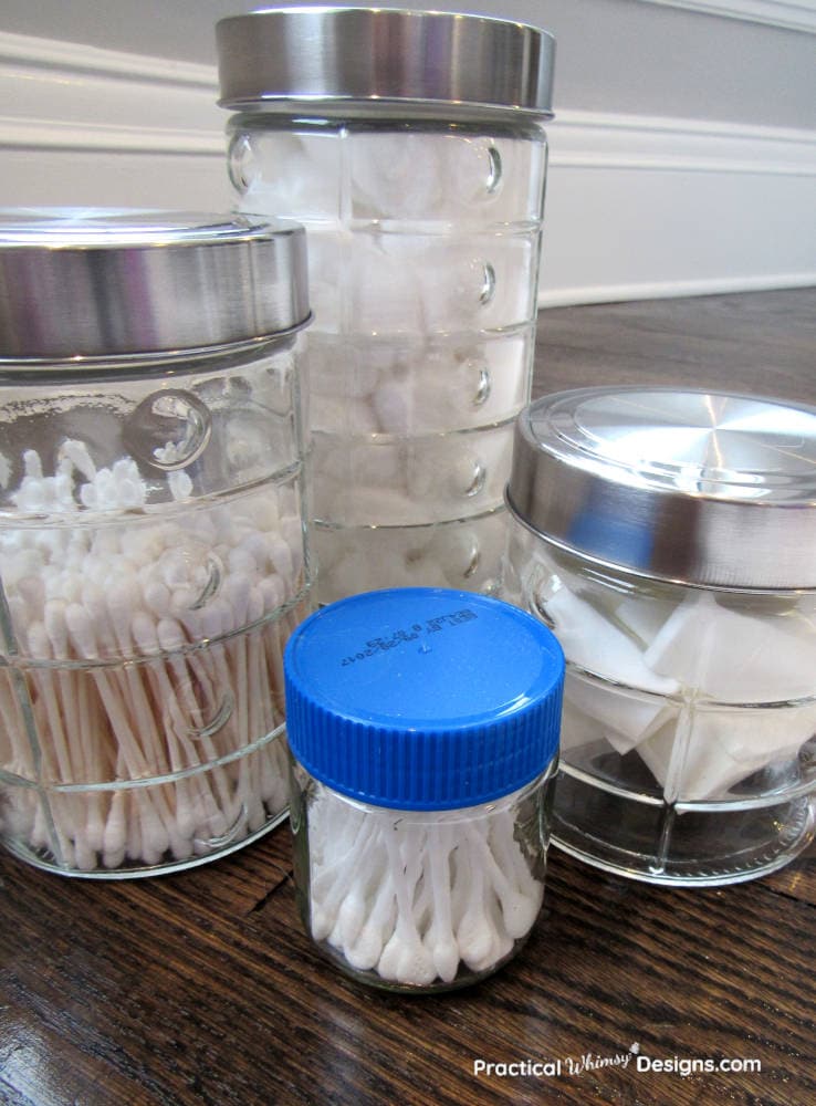 Clear glass containers used to store applicators as an easy bathroom organization hack.