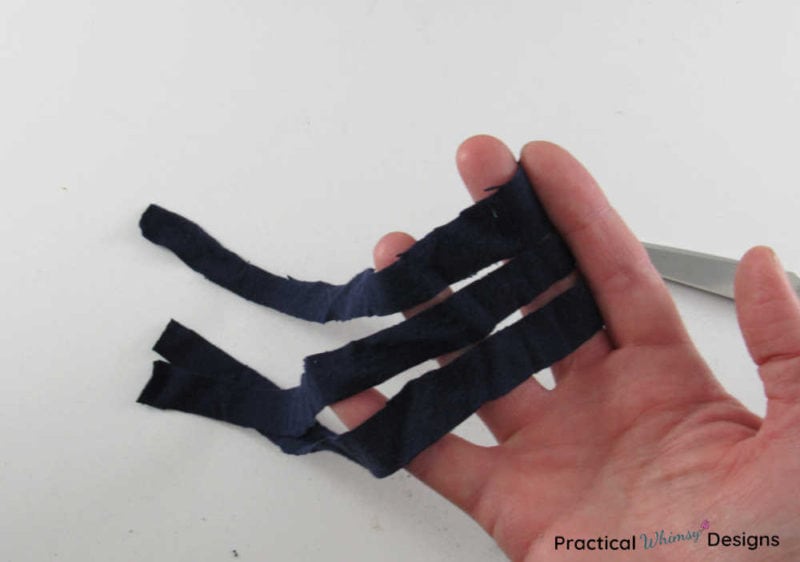 Three strips of fabric held in a hand