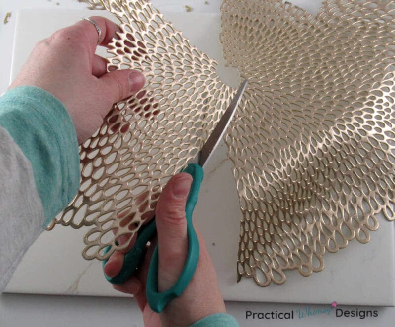 Cutting out shape in gold placemat.