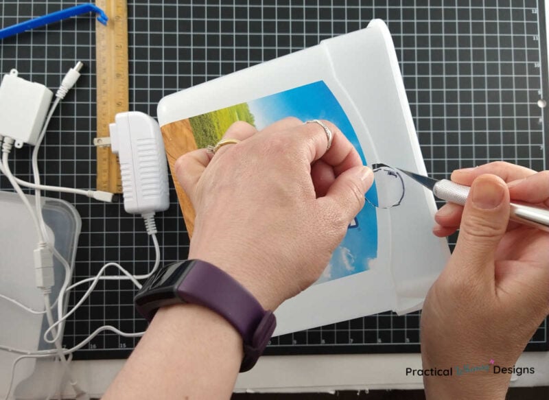 Cutting out traced circle on ice cream bucket with a craft knife.