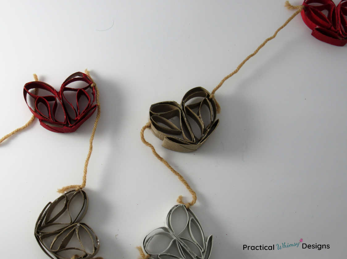 3D heart DIY Valentines garland with red, white, and brown hearts.