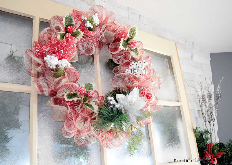 DIY mesh Christmas wreath hanging on window over mantel.