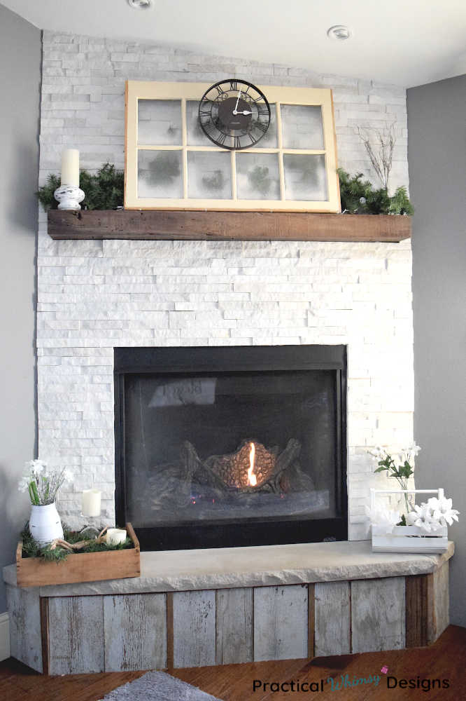 Winter fireplace with evergreens and spray snow window on mantel.