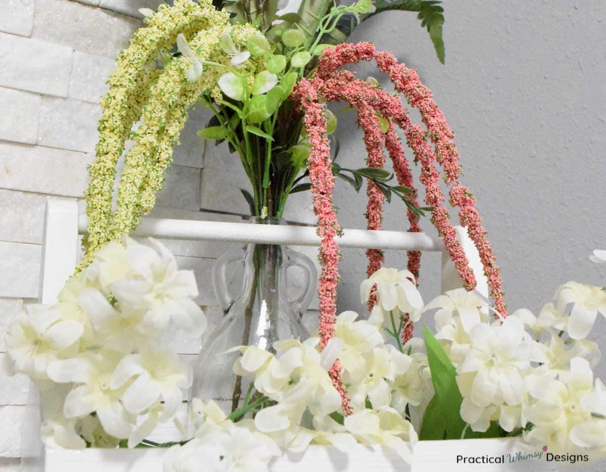 Faux white, green, and pink flowers in vase.