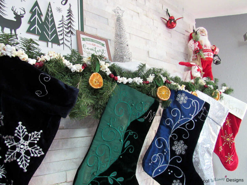 Mantel decorated with pine, popcorn and cranberry garland, dried oranges, and stockings.