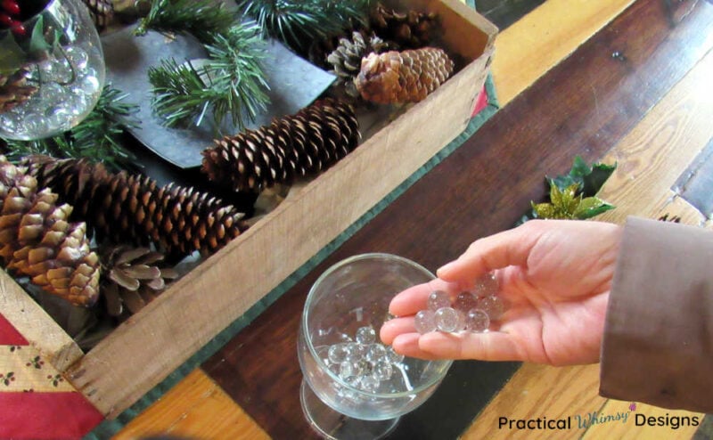 Hand dropping glass marbles in clear wine glass