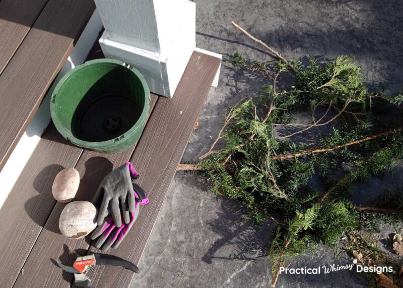 Empty pot, gloves, rocks, and evergreen boughs on a step