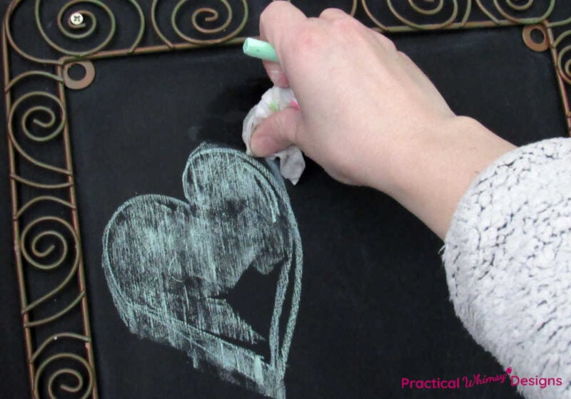 Hand erasing mistake on chalk heart with damp paper towel