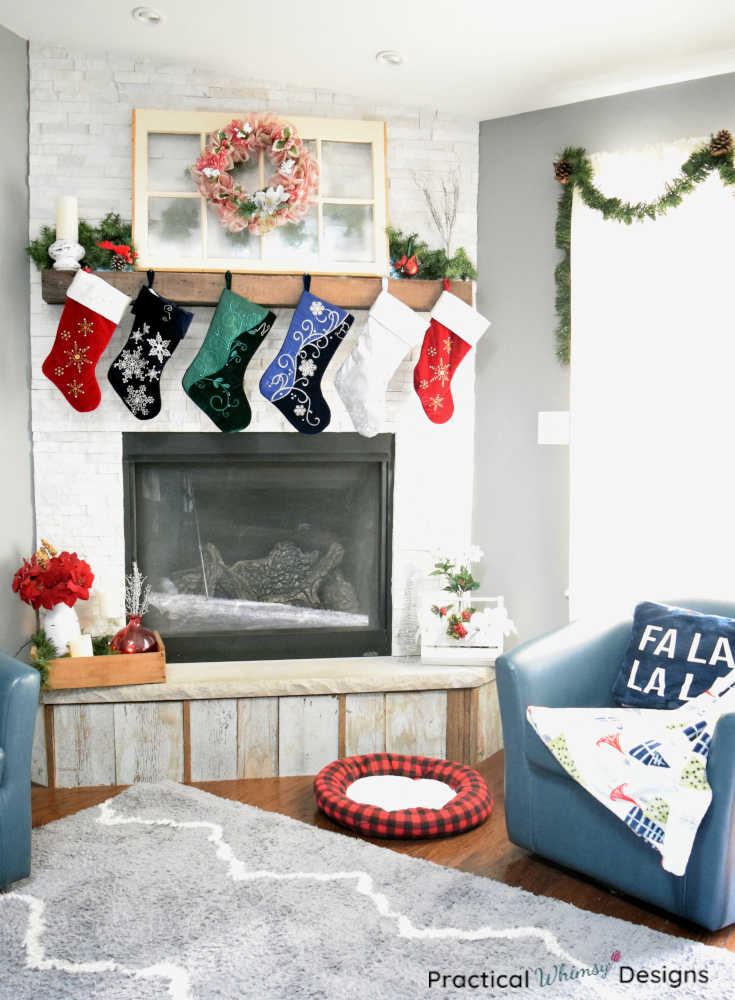 Christmas fireplace decorated with stockings, a wreath, greenery, and flowers.