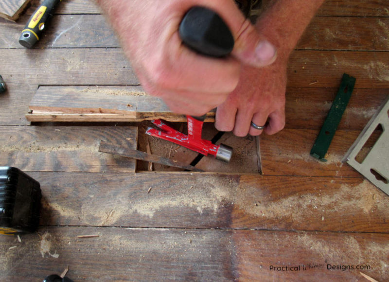 Pulling damaged hardwood floor up with hammer