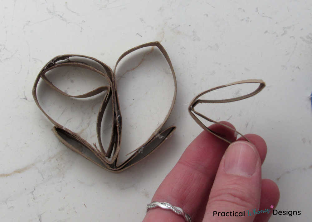 Hand holding folded v loop to glue inside of the cardboard heart.