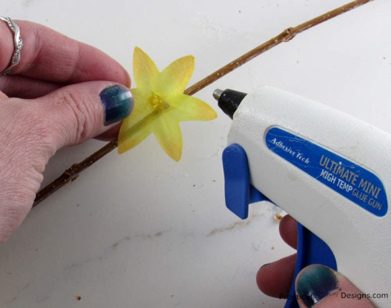 Hot gluing flowers onto branches.