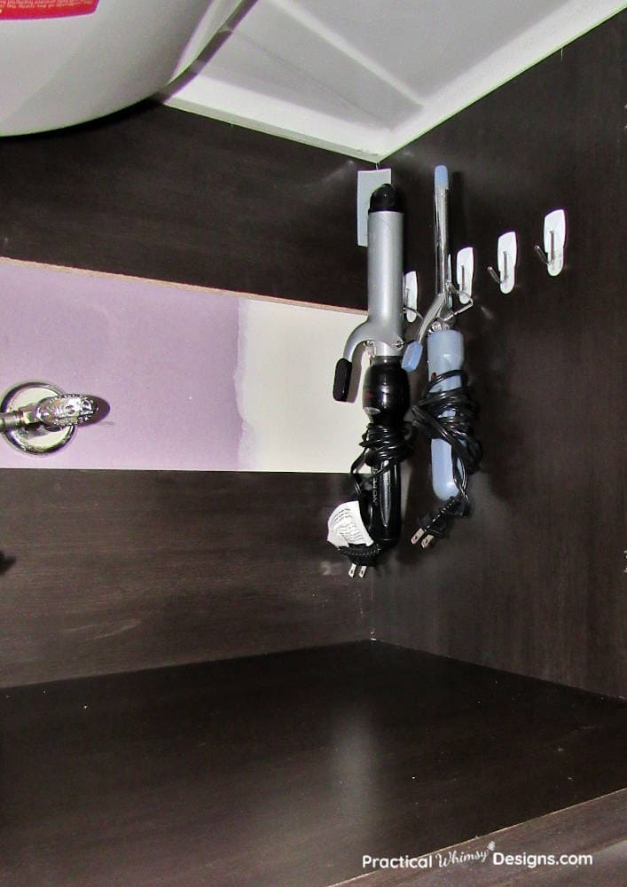 Curling irons hanging on the side of the cabinet as a small bathroom organization hack