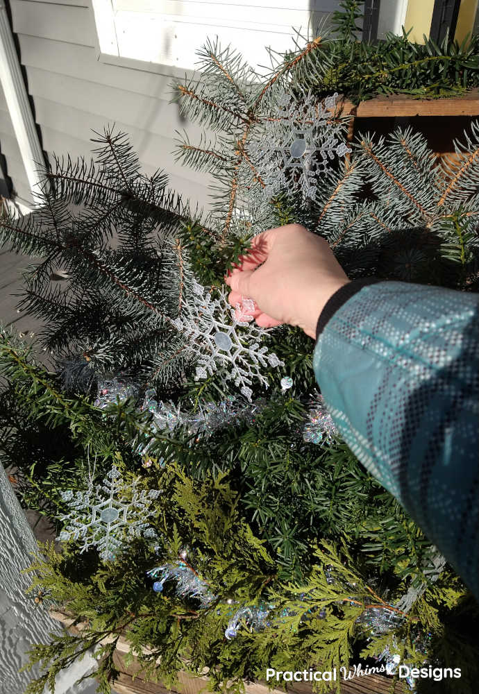 Hand hanging snowflake ornament on winter porch pot