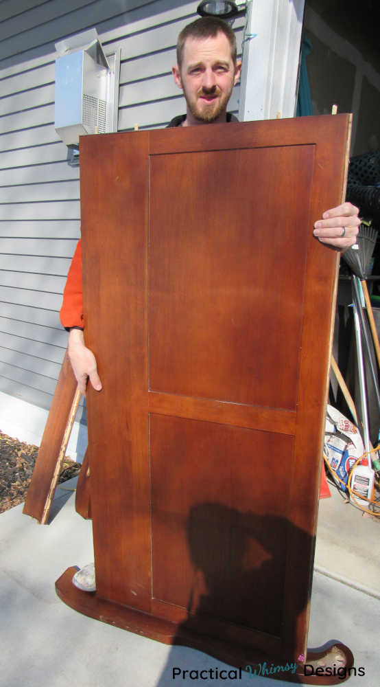 Man holding headboard after cutting it down to a smaller size