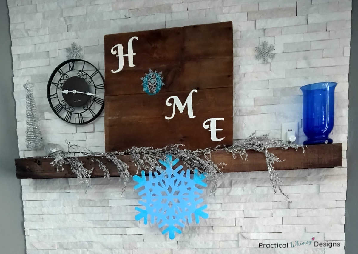 Home sign with snowflakes and clock on mantel