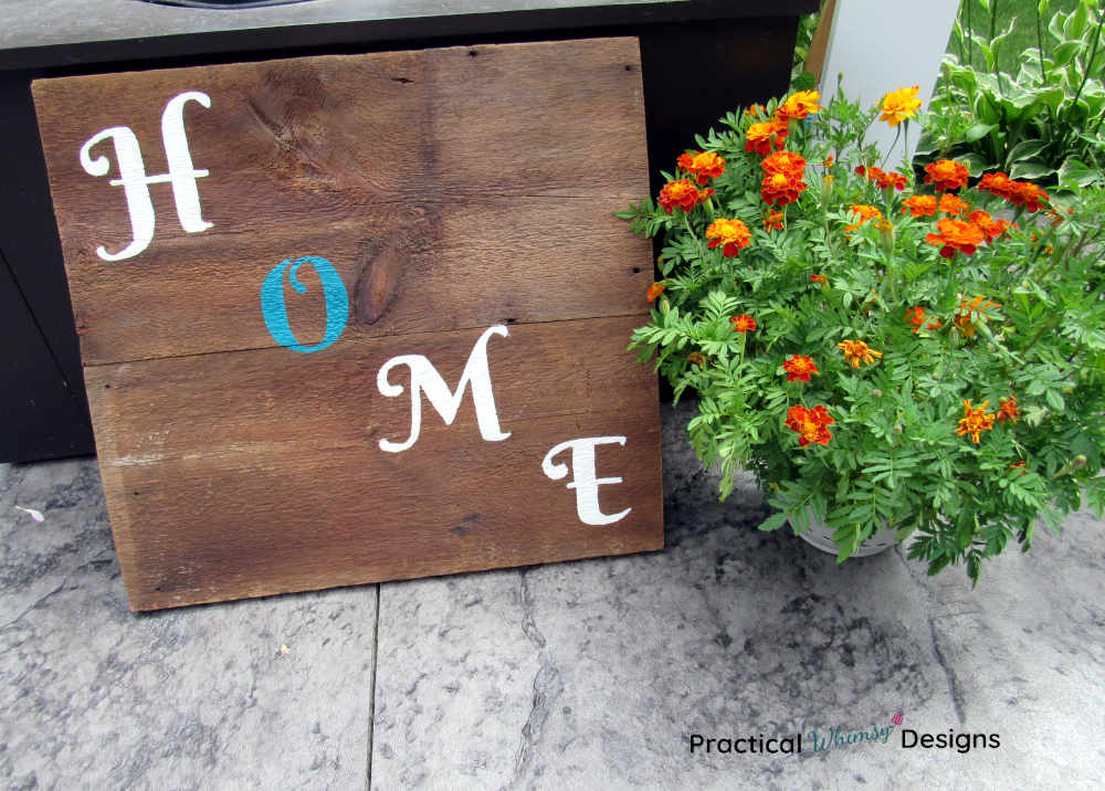 Wooden home sign next too marigold flowers