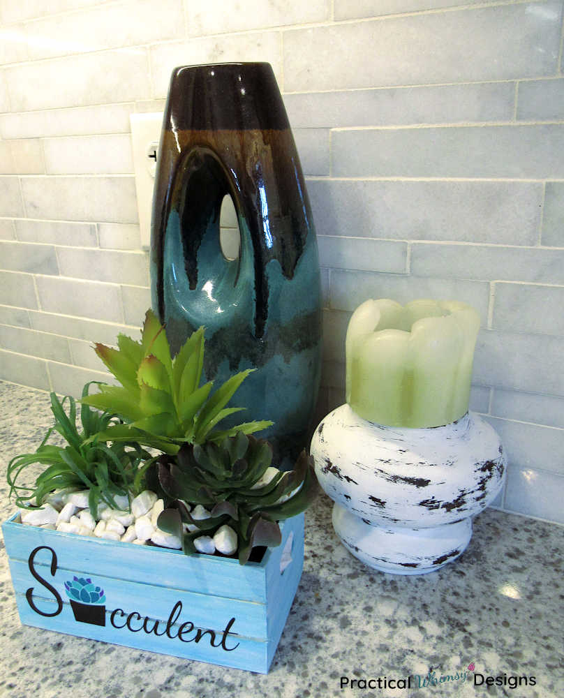 Succulent planter, farmhouse candlestick, and vase on kitchen counter.