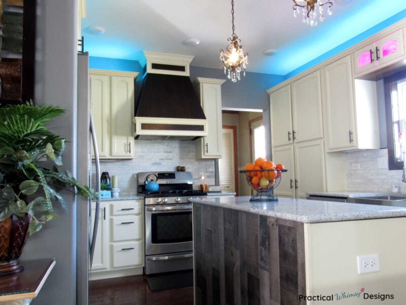 Kitchen with white cabinets, cabinet lighting, and custom stove hood vent