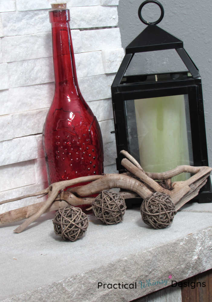 Rattan balls and drift wood in fall decor vignette with lantern and red vase.