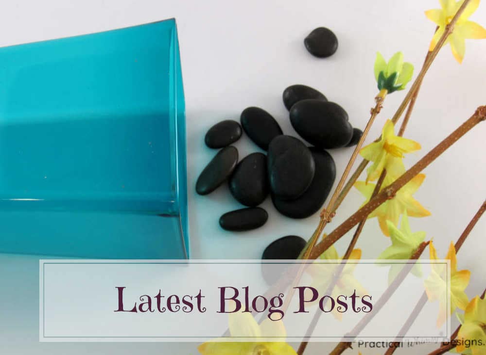 Blue vase with black rocks and yellow flowers spilled next to it