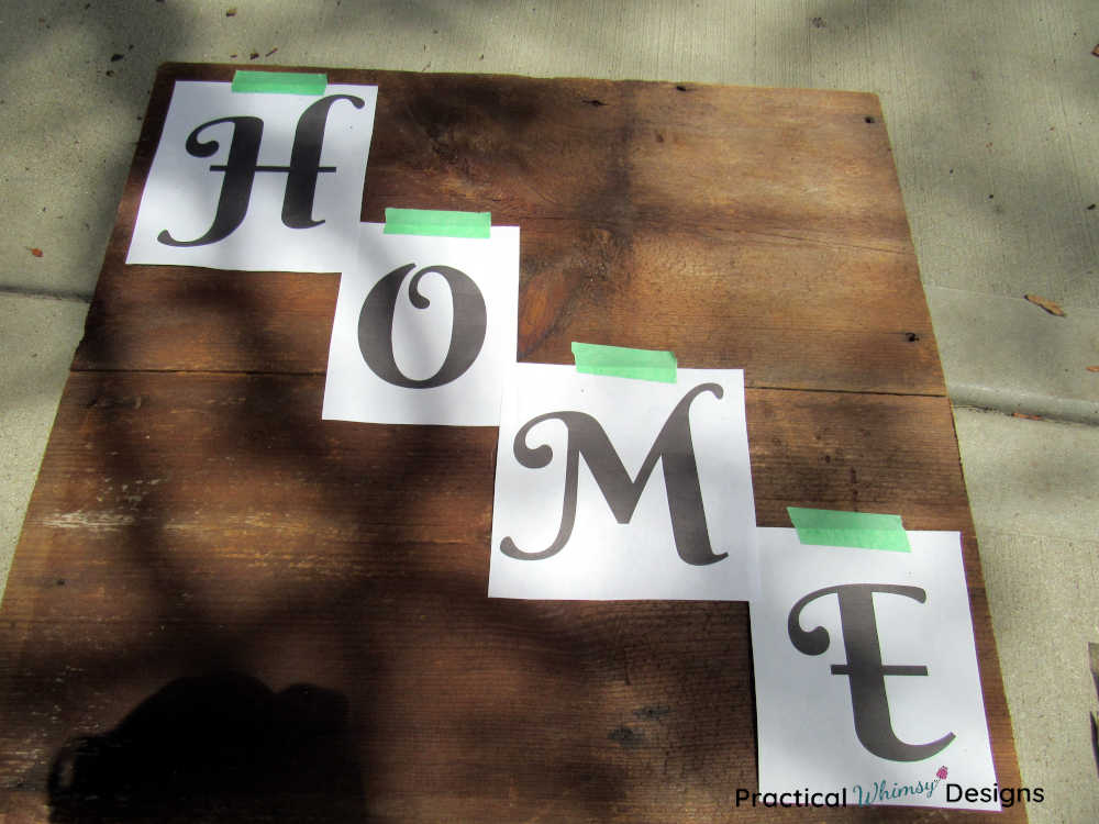 Paper letters taped to wooden board to make wooden home sign.