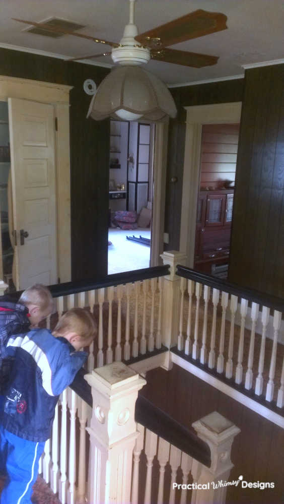 Two boys looking down over the stair railing from the second floor