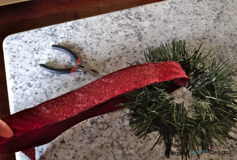 Red ribbon looped around mini wreath
